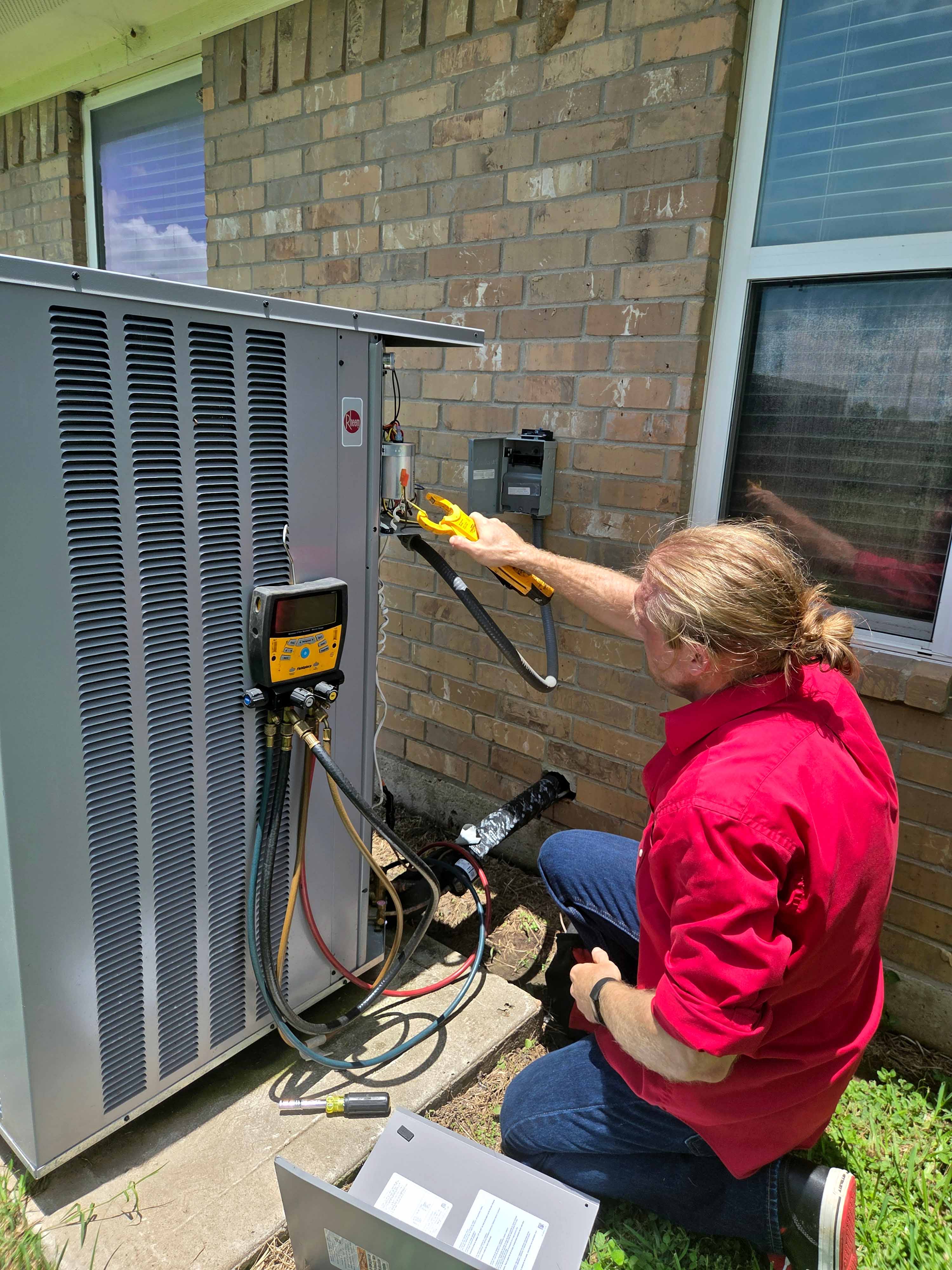 Licensed HVAC technician in Adams Air uniform walking toward residential AC unit for maintenance service