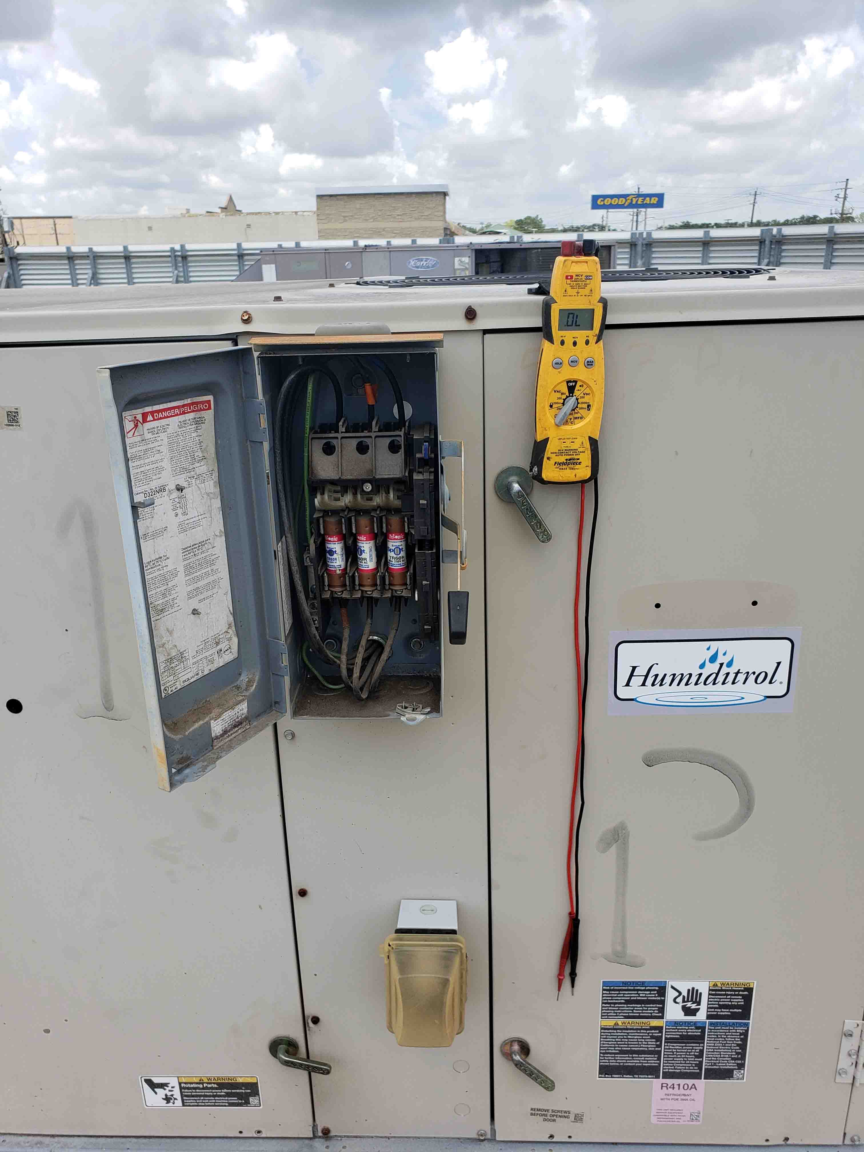 Technician using electrical meter to inspect AC fuses during comprehensive maintenance check