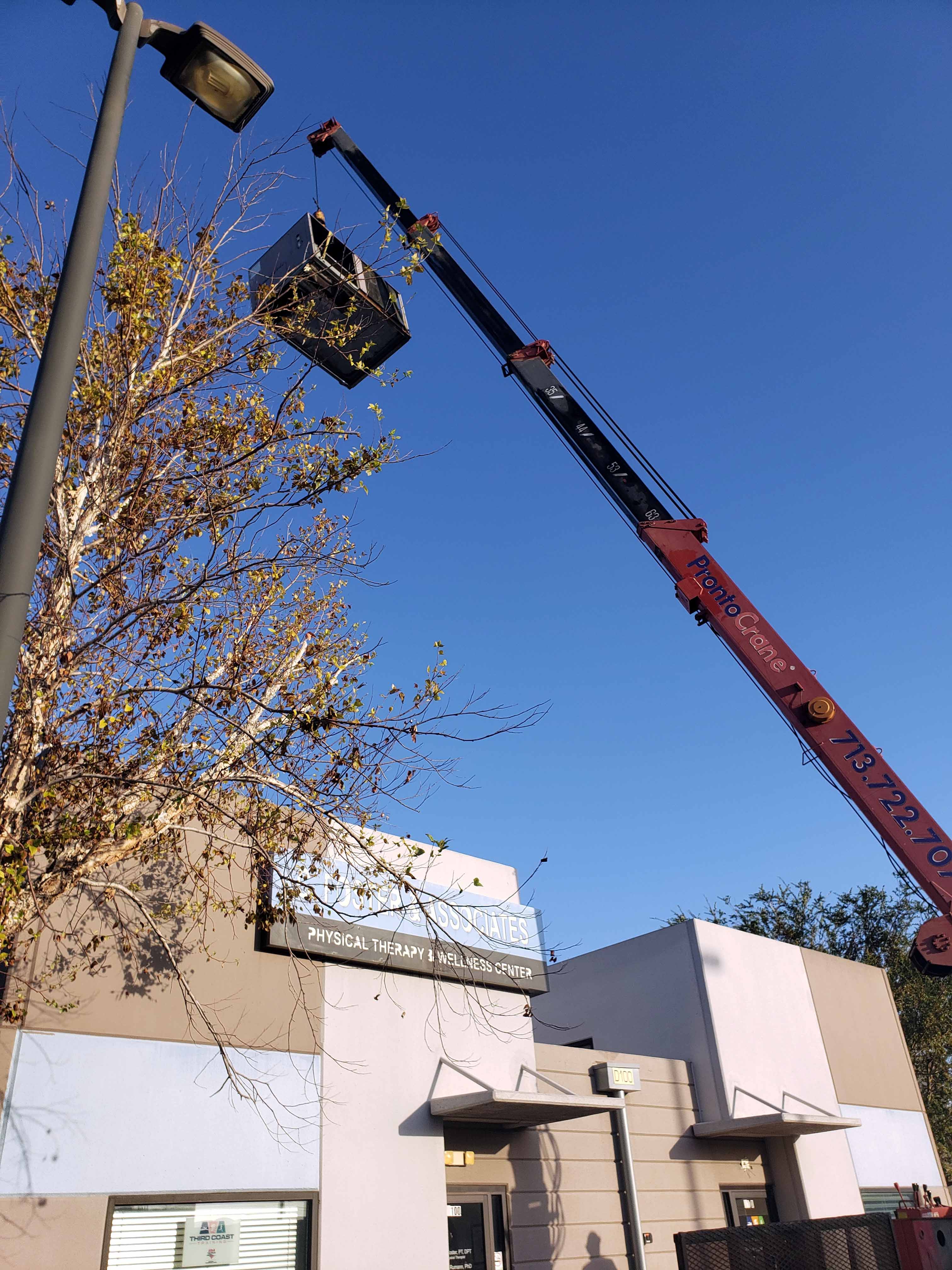 Commercial AC removal Houston - Crane truck lifting old rooftop HVAC unit from physical therapy office building